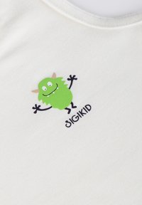 White cotton shirt featuring a green cartoon monster graphic with outstretched arms and the text "SIGIKID" below. Smooth texture, simple design.