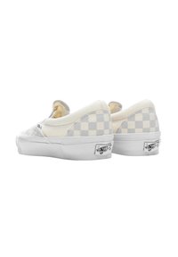 Sneaker slip-on senza lacci in tela a scacchi crema e grigio con suola in gomma bianca e logo Vans sul tallone. Texture morbida.