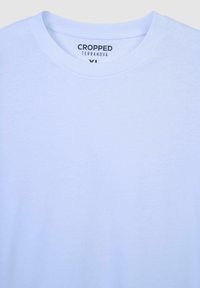 Skrojona jasnoniebieska koszulka z miękkiego materiału, z okrągłym dekoltem oraz metką z napisem "CROPPED TERRANOVA" i rozmiarem XL.