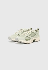 Pantofi sport de culoare verde deschis, cu panouri din plasă și accente din suede. Prezintă o talpă cu amortizare, șireturi tonale și o talpă din cauciuc pentru aderență.