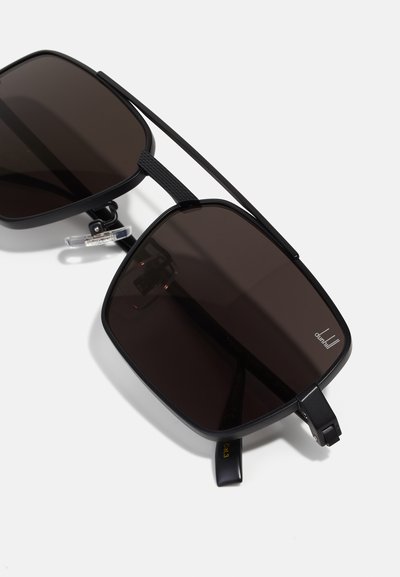 Occhiali da sole rettangolari neri con lenti scure, finitura opaca e un design del ponte unico. Presentano naselli regolabili e dettaglio del logo.