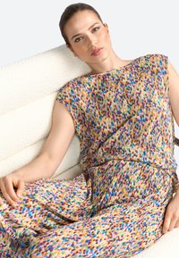 Multicolored pleated dress with a round neckline, featuring a vibrant pattern of dots in blue, green, yellow, and red shades. Lightweight fabric.