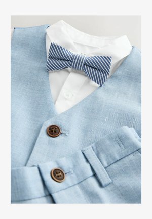 Jasnoniebieska denimowa kamizelka z białą koszulą pod spodem. Uzupełniona o paskowany niebiesko-biały muszkę oraz brązowe guziki na kamizelce.
