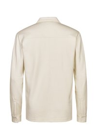 Camisa de manga larga en color crema, con cuello clásico, puños con botones y detalles cosidos en la espalda. Fabricada con tela suave.