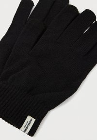 Μαύρα πλεκτά γάντια με ribbed μανσέτα, διαθέτουν μια μικρή ετικέτα με κείμενο. Η υφή είναι ομαλή και ελαστική, κατάλληλη για χειμωνιάτικη χρήση.