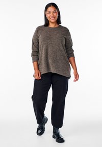 Brązowy sweter dzianinowy z teksturowanym wzorem, z długimi rękawami i okrągłym dekoltem, w połączeniu z czarnymi spodniami o luźnym kroju i czarnymi botkami.