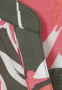 Blumenstoff in verschiedenen Rosa-, Weiß- und Grüntönen. Das Design zeichnet sich durch eine weiche Textur und kontrastierende Nähte an den Rändern aus.