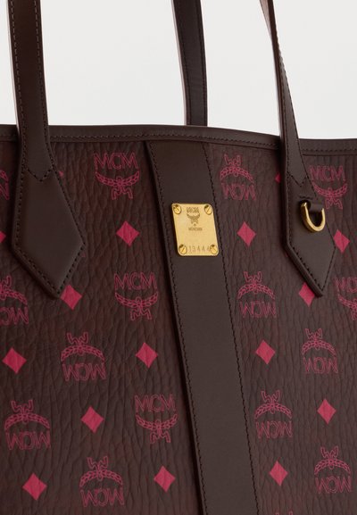 Sac cabas en cuir texturé marron avec motif logo MCM rose, plaque logo en métal doré et deux bandoulières avec détails cousus.
