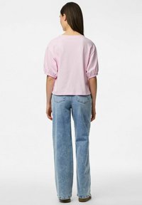 Lyhythihainen vaaleanpunainen puuvillapaita, jossa on rento malli, yhdistettynä vaaleansinisiin, leveisiin farkkuliiveihin. Yksinkertainen muotoilu ilman koristeita.