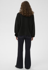 Sort fleecepullover med lange ærmer og løs pasform, kombineret med mørkeblå vidde jeans med klassisk fem-lomme-design.