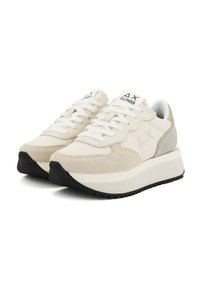 Beige Sneaker mit Obermaterial aus Wildleder und Mesh, weißen Schnürsenkeln, einer auffälligen weißen Mittelsohle und einer strukturierten schwarzen Gummisohle. Akzentuiert mit einer grauen Ferse.