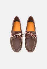 Braune Lederbootsschuhe mit weißen Akzenten, klassisches Design, runde Spitze und cremefarbener Naht, mit beigen Schnürsenkeln und orangener Innensohle.