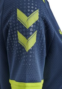 Sporttrui gemaakt van ademende meshstof. Donkerblauw met lichtgroene chevronpatronen en een effen groene accent aan de zoom.