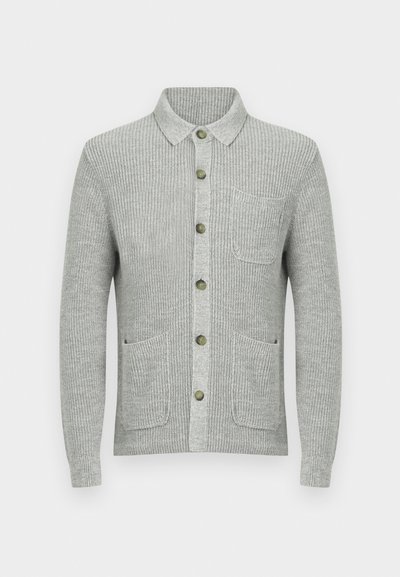 Pilka raukinė megzta rankovėmis megztinė su apykakle, priekyje užsegama mygtukais ir dviem šoninėmis kišenėmis. Yra žali mygtukai ir kišenė kairėje krūtinės pusėje.