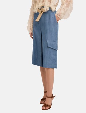 Culotte in denim con vita alta, cintura beige, tasche laterali e vestibilità rilassata in azzurro chiaro. Abbinati a tacchi a strappo marroni.