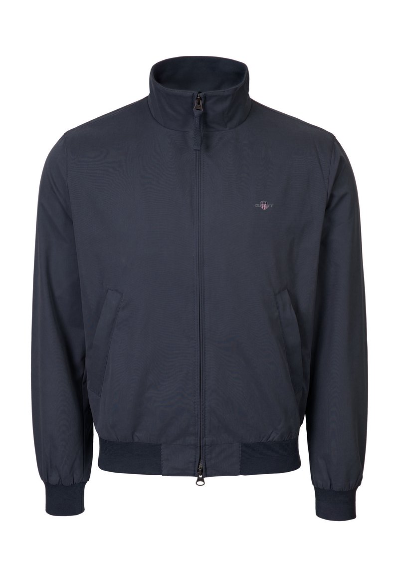 Giacca blu navy con zip, collo alto, polsini e orlo a coste, tasche laterali e piccolo logo sul petto a sinistra.