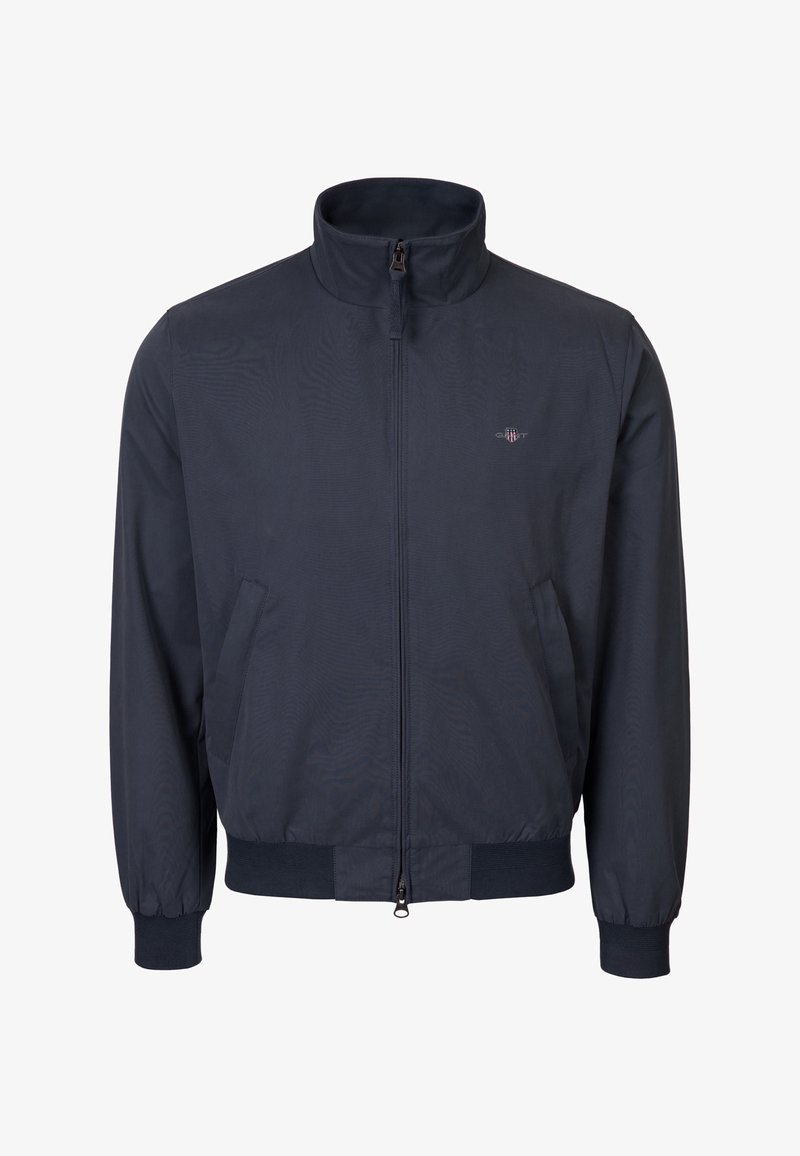 Giacca blu navy con zip, collo alto, polsini e orlo a coste, tasche laterali e piccolo logo sul petto a sinistra.