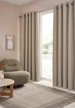Beige Vorhangpaneele an einer Schiebetür aus Glas in einem neutral gehaltenen Wohnzimmer mit einem strukturierten Sessel, rundem Holztisch und geometrischer Wandkunst.