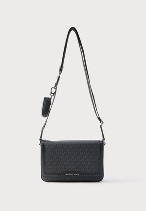 Czarna torba na ramię Michael Kors z monogramem, klapką zamykającą, regulowanym paskiem oraz dołączoną małą, okrągłą saszetką na monety.