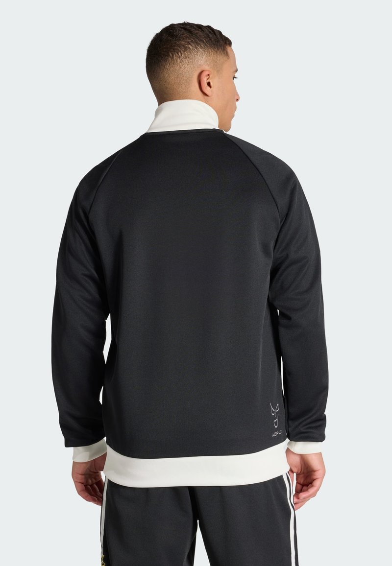 Sweat-shirt de sport noir avec un col montant, un accent blanc à l'ourlet et une texture lisse. Il comporte des manches raglan et un détail logo.