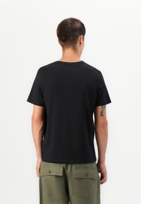 Zwarte katoenen t-shirt met korte mouwen, ronde halslijn en een gladde textuur. Draag het met een groene cargobroek met grote zakken.