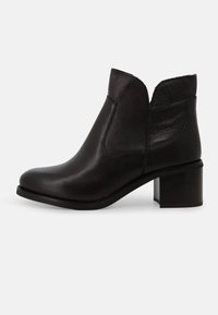 Stivaletto alla caviglia in pelle nera con dettagli strutturati, punta arrotondata e tacco a blocco. Presenta un design con ritagli nella parte superiore per un aspetto moderno.