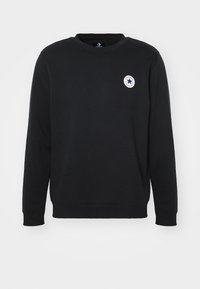 Sudadera negra hecha de una mezcla de algodón, con cuello redondo, mangas largas y un pequeño logo circular en el pecho.