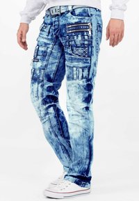 Pantaloni cargo in denim blu sbiadito con numerose tasche, cerniere e un design testurizzato. Presentano una vestibilità dritta e passanti per cintura.