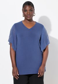 Top blu V con scollatura a V e maniche corte fluide, con decorazioni sulle maniche. Realizzato in tessuto morbido, ha una vestibilità ampia e spacchetti laterali.