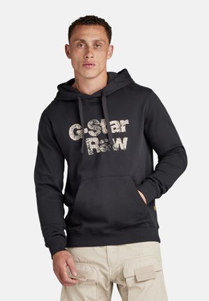 Black hoodie made of cotton blend, featuring a front pouch pocket and large "G-Star Raw" printed in distressed font. Seamless cuffs.