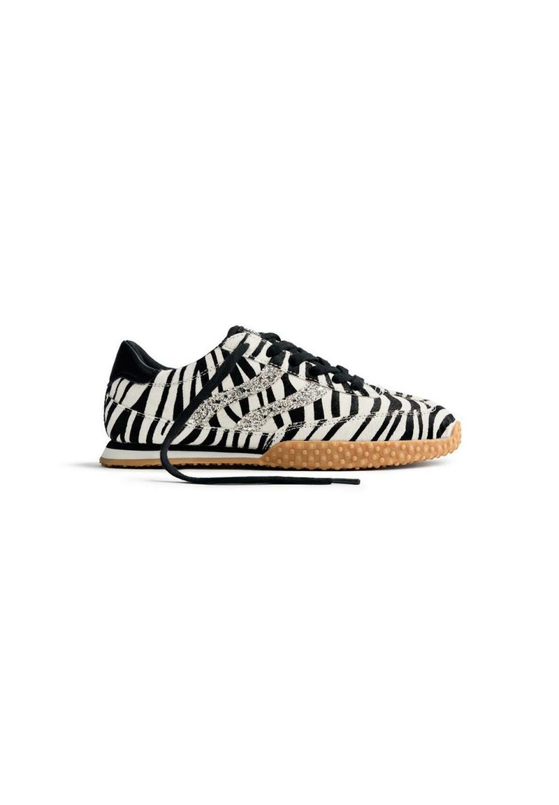 Sneaker a strisce zebra bianco e nero con suola in gomma, lacci neri e tomaia testurizzata. Presenta una silhouette bassa e accenti a contrasto.