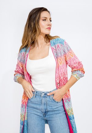 Un cardigan leggero e colorato con un motivo geometrico in rosa, blu e arancione, con apertura frontale e maniche arrotolate.