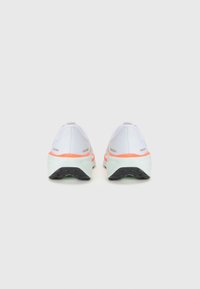 Chaussures de sport blanches avec une tige en mesh, des accents orange et gris, et une semelle noire texturée. Talon courbé et détails réfléchissants présents.