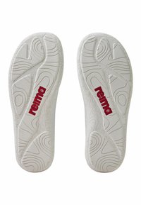 Vita gummisulor med texturerad yta och röd "reima"-logotyp. Har vågiga mönster och spår för förbättrat grepp och komfort.