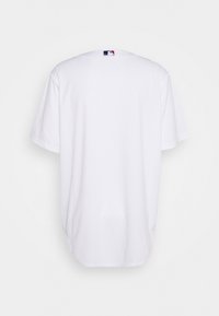 Vit t-shirt med kort ärm i mjuk bomull, med rundad halsringning och en liten MLB-logotagg på baksidan. Slät textur.