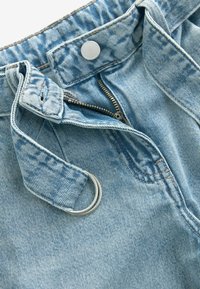 Ljust blå denimjeans med dragkedja, silverknapp och bältesöglor. Har en silver D-ring som detalj vid midjan och strukturerad tyg.