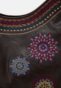 Mörkbrun läderväska med intrikata flerfärgade blommönster i orange, blått, lila och vinrött runt den övre kanten.