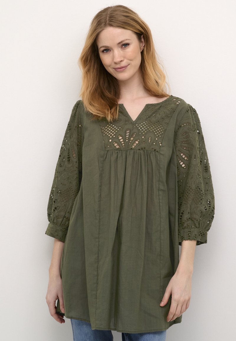 Olivgrön blus med V-ringning, broderade detaljer och ballongärmar. Tillverkad av lätt tyg, med en rynkad kroppsstil.