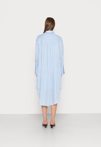 Abito camicia a righe blu chiaro con vestibilità comoda, colletto a camicia, maniche lunghe e orlo curvato, realizzato in un tessuto leggero.