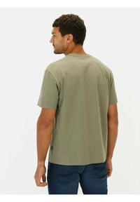 Oliven grøn t-shirt lavet af bomuld med korte ærmer, rund halsudskæring og lige snit, vist fra ryggen mod en hvid baggrund.