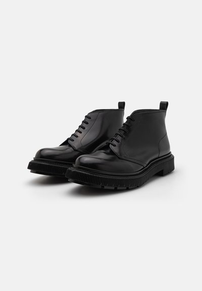 Zwarte leren enkellaarzen met een ronde neus, vetersluiting aan de voorkant en ribbelrubber zool. Voorzien van treklussen voor gemakkelijk aan- en uittrekken.