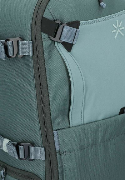 Zaino verde caratteristiche in materiale sintetico texturizzato, con più cinghie regolabili, una tasca laterale e un compartimento con zip.