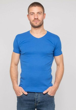 T-shirt bleu à manches courtes et décolleté en V, au design ajusté, fabriqué dans un matériau lisse avec un minimum de détails de marque. Porté avec un denim décontracté.