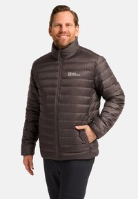 Puffer jacket in dark brown, quilted design with high collar, front zipper, side pockets, and logo on the left chest.