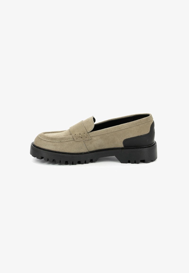 Mocassin en daim beige avec talon en caoutchouc noir et semelle crantée épaisse, profil latéral visible.