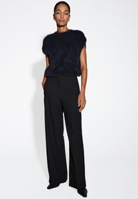 Haut en tricot texturé bleu marine à manches courtes associé à un pantalon large noir taille haute. Tissu lisse et détails de design minimalistes.