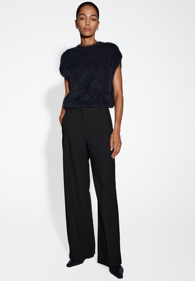 Haut en tricot texturé bleu marine à manches courtes associé à un pantalon large noir taille haute. Tissu lisse et détails de design minimalistes.