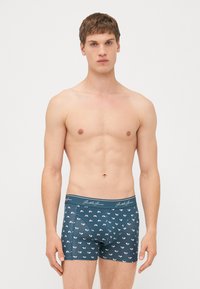 Männliche blaue Boxershorts mit einem weißen Bergmuster, elastischem Bund und enganliegender Passform. Hergestellt aus weichem, dehnbarem Stoff für zusätzlichen Komfort.