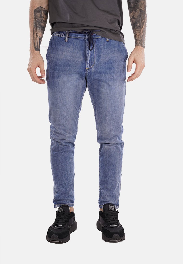 Jeans in denim blu chiaro con una vestibilità slim, vita con cordoncino e una leggera scoloritura. Abbinati a sneaker nere per un look casual.