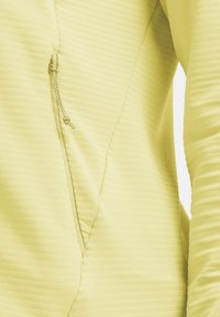 Gelber strukturierter Pullover mit diagonaler Reißverschlusstasche, versehen mit feinen horizontalen Streifen und figurbetontem Schnitt. Weicher Stoff mit glattem Finish.